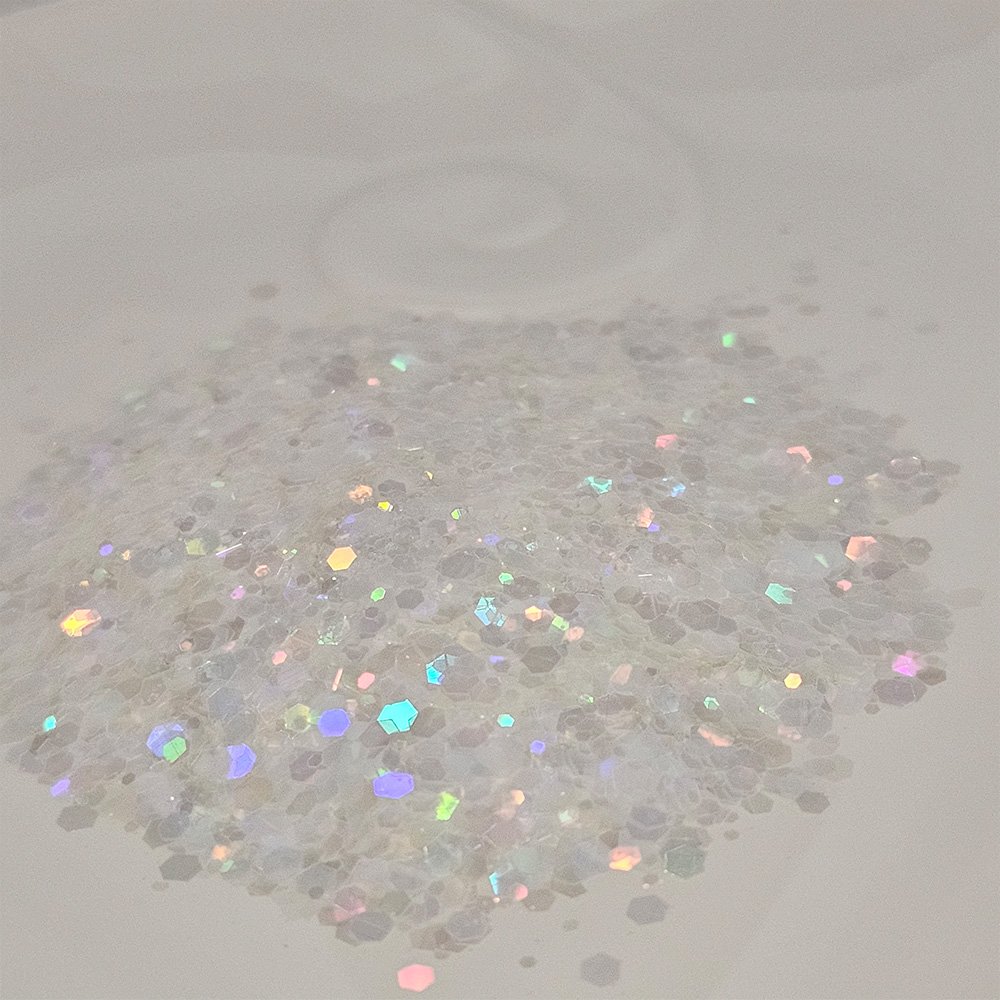 Clear iridescent chunky glitter with rainbow reflection on a soft neutral background